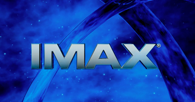 The silver IMAX logo centered over a blue background with swirling cosmic patterns and stars.