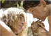 A man and a woman with blonde and dark hair gaze intensely at one another in a close-up shot.