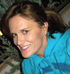 A woman with brown hair smiling while wearing a bright blue hooded sweatshirt.