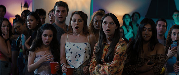 A group of diverse young people looking forward with wide eyes and open mouths in shock.