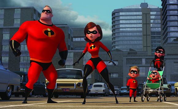 The Incredibles family in red superhero suits standing in a city street with buildings and cars in the background.