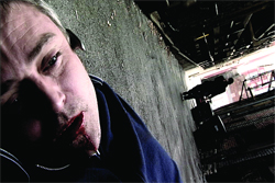 Close-up of a man lying on concrete with blood visible around his mouth.
