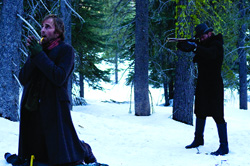 A man in a dark coat smokes a pipe in the foreground while another man aims a rifle in a snowy forest.