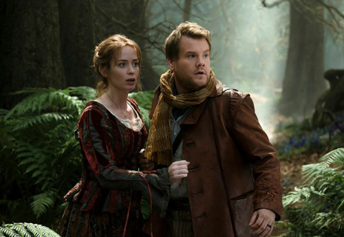 A woman in a red velvet dress and a man in a brown leather jacket look startled in a misty forest.