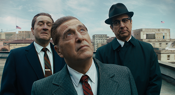Three men in vintage suits and hats looking up toward the sky on a rooftop.
