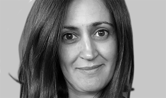 Black and white close-up portrait of a woman with long dark hair looking at the camera.