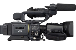 A black JVC professional video camcorder with a large lens and a shotgun microphone attached to the top handle.