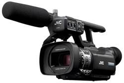 A black JVC professional video camera with a large foam-covered microphone attached to the top.