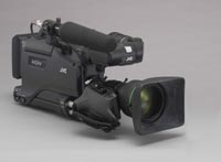 A black professional video camera with a large lens and a microphone on top, set against a gray background.
