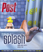 A man with a rubber duck on his head peeks over the edge of a bathtub, with his legs and feet visible.
