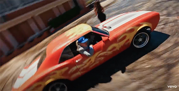 A red muscle car with yellow flame decals driving fast on a dirt road.