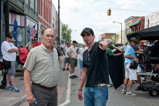 A film crew stands on a city street with cameras and equipment during a production.