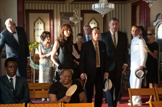 A group of people in formal suits and dresses walking through a decorated room.