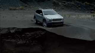 A silver SUV parked on dark, volcanic-like soil near a steep cliff edge.
