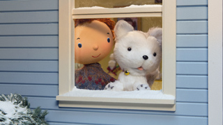 A cartoon boy and a white fluffy dog looking out of a snow-dusted window of a blue house.