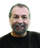 A smiling man with salt and pepper hair and a beard wearing a black shirt.