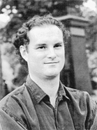 Black and white portrait of a young man with curly hair wearing a button-down shirt.