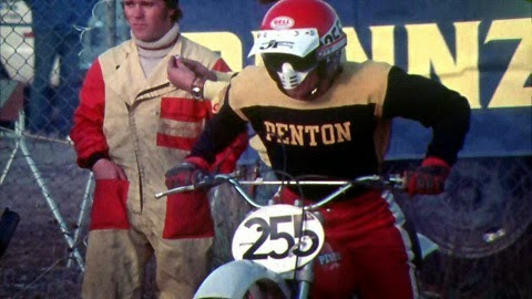 A motocross rider in a red helmet and black and yellow jersey riding a motorcycle with number 255.