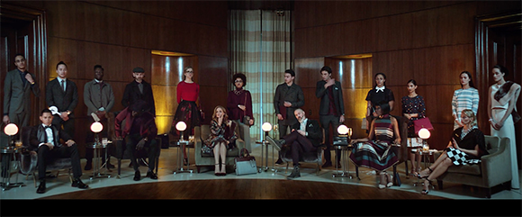A group of people in formal attire posing in a large, wood-paneled room with warm lighting.