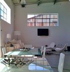 A bright, minimalist room with white walls, a glass dining table, and white modern furniture.