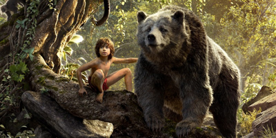 A young boy sits on a mossy log next to a large, furry brown bear in a sunlit jungle.