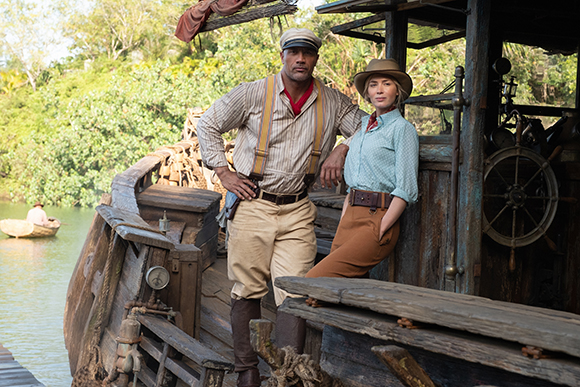 A man in a striped shirt and cap and a woman in a blue shirt and hat lean against a wooden boat.