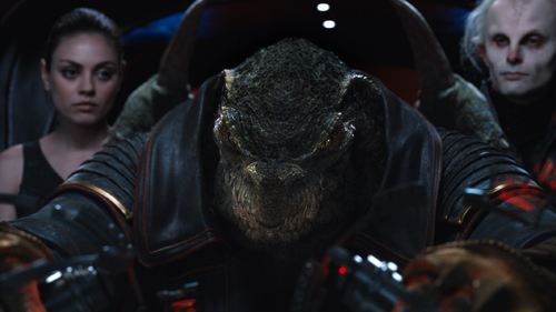 A close-up of a textured, reptilian creature's head in a dark, cinematic environment.