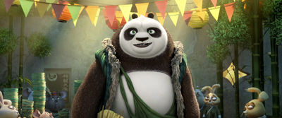 A large, smiling panda wearing green fabric wraps stands in a village decorated with colorful bunting.