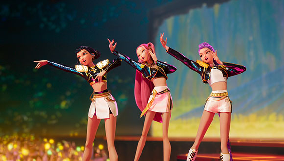 Three animated female characters in colorful outfits performing a synchronized dance on a brightly lit stage.