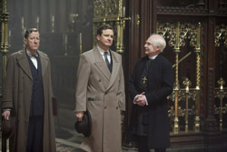 Three men in formal attire stand together in a dark, wood-paneled room with gold accents.