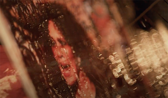 A blurry, close-up view of a person's face seen through a textured, reflective surface with light bokeh.