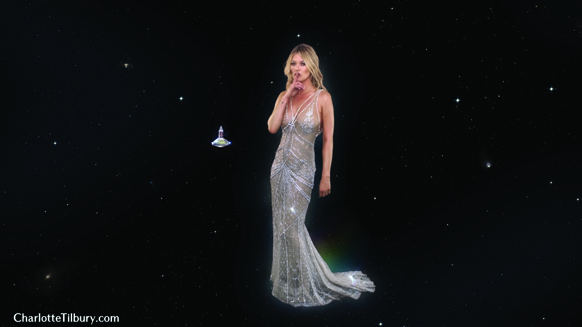 A woman in a sparkling silver dress floating against a dark, starry space background near a small UFO.