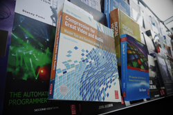 Close-up of books on a shelf, featuring a book about video and audio compression. Other titles are partially visible.