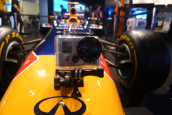 GoPro camera mounted on the front of a yellow and red Formula 1 race car, showing the cockpit and tires.