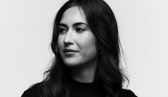 Black and white portrait of a woman with long dark hair looking off-camera against a light background.