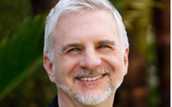 A smiling man with short gray hair and a gray beard looking toward the camera.