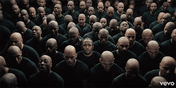 A dense crowd of men wearing black shirts, looking toward the camera with serious expressions.