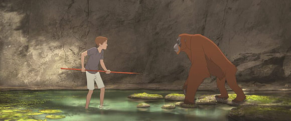 A young boy holding a long stick stands in a shallow pool facing a large orangutan near a rocky cave wall.