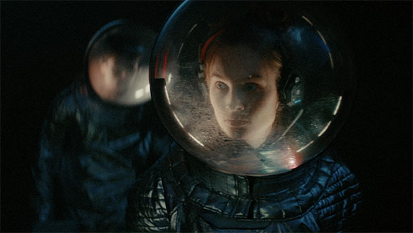 Two astronauts wearing glass helmets in a dark, cinematic setting.