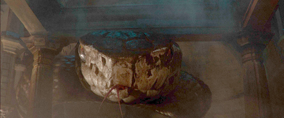 A close-up of a massive, pale snake head emerging in a dimly lit, stone-pillared room.