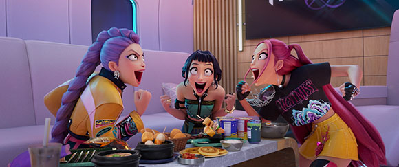 Three animated women with colorful hair sit around a table filled with various dishes and snacks.