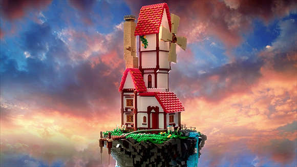 A toy windmill house built of bricks sits on a floating island against a colorful sunset sky.