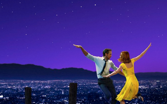 A man in a light shirt and a woman in a yellow dress dance joyfully against a purple starry night sky.