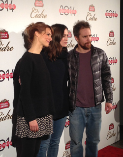 Three people stand together in front of a backdrop with logos for Stella Artois Cidre and 2014.