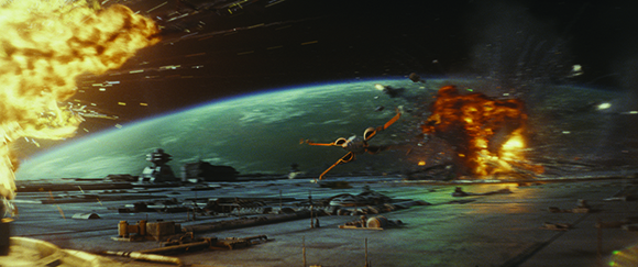 A small spacecraft flies over a massive ship near a green planet during a space battle with explosions.