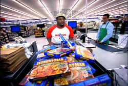 A customer at a grocery checkout lane with a cashier in the background.