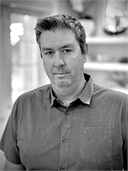 Black and white portrait of a middle-aged man wearing a short-sleeved button-down shirt.