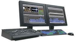 Two computer monitors displaying video editing software next to a keyboard and a control console.