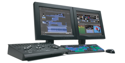 Two computer monitors displaying video editing software next to a control console, keyboard, and mouse.