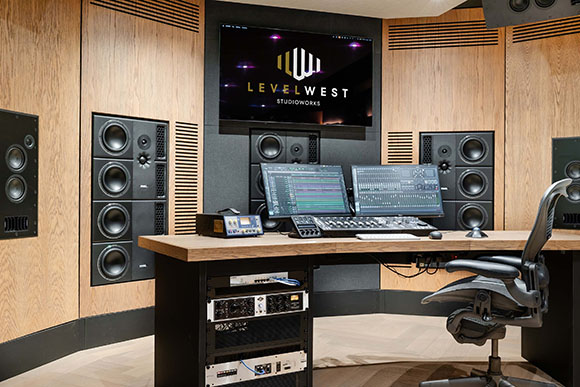 A recording studio control room featuring large studio monitors, dual computer screens, and a mixing desk.